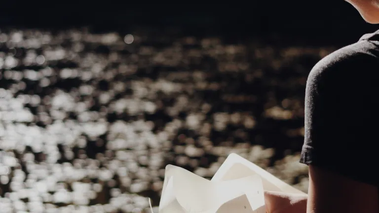 Une femme lit la Bible à côté d'un lac