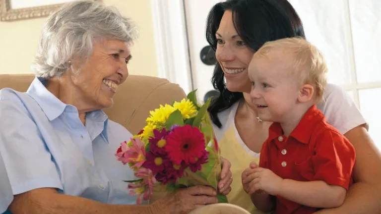 Un petit garçon et sa maman donne des fleurs à sa grand-mère