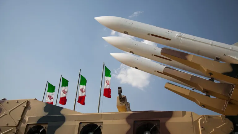 « Le problème insoluble des ambitions nucléaires de l’Iran — et la menace à l’égard d’un Israël de plus en plus inquiet — semblent avoir atteint un point critique. » Un groupe de missiles. En arrière-plan, des drapeaux de l'Iran.