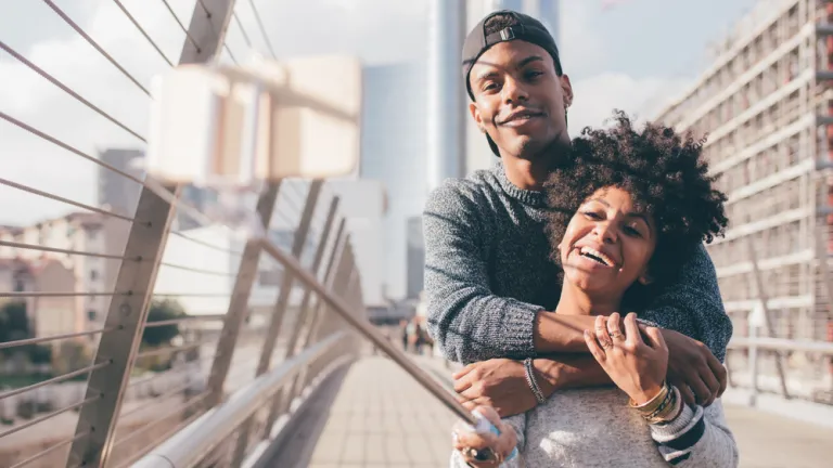 Un jeune homme et une jeune femme se tiennent dans les bras et prennent un selfie.