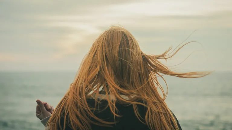 Une adolescente debout près d'un mur de briques.