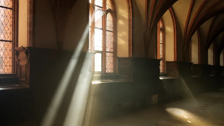 Des rayons de soleil traversent les fenêtres d'une vieille église.