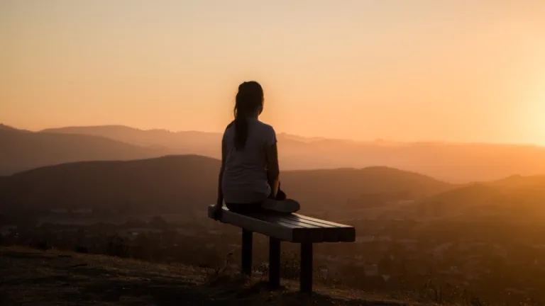 Jésus veut que nous suivions Son exemple en surmontant la tentation et le péché par la puissance du Saint-Esprit. Une femme assise sur un banc regardant le coucher du soleil.