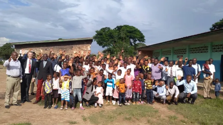 Photo de groupe de membres de l'Église de Dieu Unie en Afrique devant leur salle d’assemblée