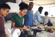 Famille multiraciale heureuse avec trois enfants cuisinant ensemble à la maison