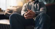 Anxiété, mains et thérapie avec une personne assise sur un canapé dans un cabinet pour un rendez-vous de consultation ou de counseling.