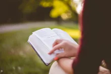 Une femme tenant une Bible sur ses genoux.