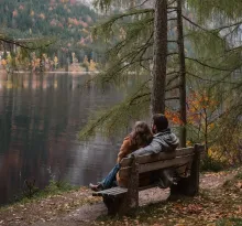 Couple sur banc avec vue sur un lac, en automne