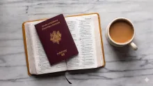 un passeport sur une bible ouverte près d'une tasse de café