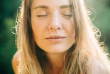 Portrait rapproché d’une femme aux yeux fermés, baignée par une chaude lumière naturelle du soleil