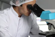 Une personne regardant à travers un microscope.