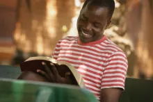 Un homme sourit en lisant sa Bible