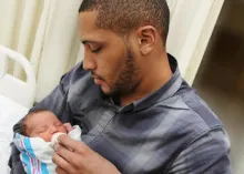 Un nouveau papa tenant son bébé.