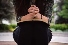 Une femme lit sa Bible avec des mains croisées en prière