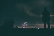 Une personne debout à l'extérieur, regardant les étoiles dans le ciel.