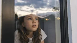 Une petite fille qui regarde par la fenêtre.