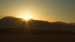 Le soleil qui se couche sur une chaîne de montagnes.