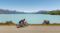 Vue en hauteur d'un homme et sa fille faisant du vélo à côté du lac Pukaki en été