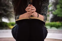 Une femme lit sa Bible avec des mains croisées en prière
