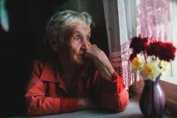 Une vieille dame regarde par la fenêtre