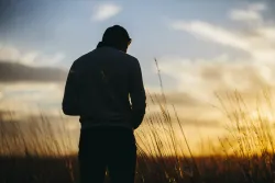 Silhouette d'un jeune homme avec le soleil couchant en arrière-plan.